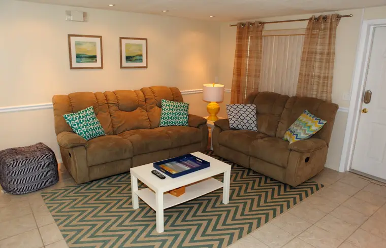 Living room with two recliner sofas, wall-mounted TV, and chevron rug, Happy Turtle B